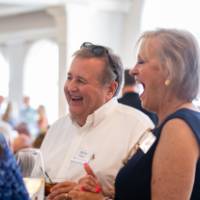 Kevin Moore and woman standing around event table, laughing in response to something said